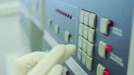 scientist in white glove is clicking on hardware buttons of equipment