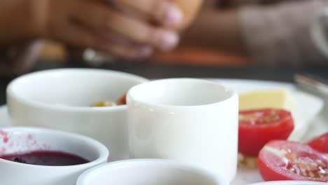 breakfast scene with egg, tomatoes, butter and jam.