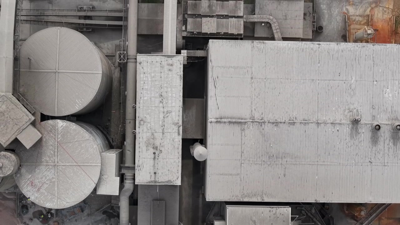 Et luftfoto viser et industrikompleks med bygninger, rør og byggematerialer, som fremhever byutvikling og infrastruktur