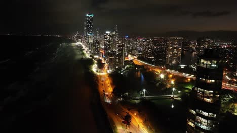 Looking-south-at-twilight-on-the-iconic-Surfers-Paradise-beachfront,-hovering-high-over-sparking-waves-of-Gold-Coast-beaches