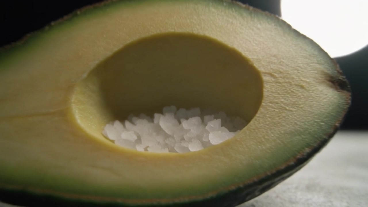 Mezzo avocado riempito con cristalli di sale marino su sfondo scuro