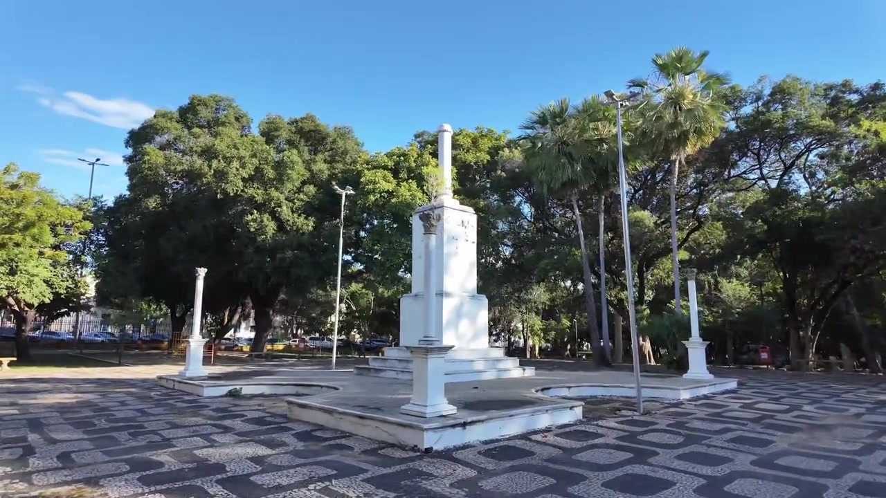 Brezilya'nın Teresina şehrinde sakin bir halk meydanında desenli taş kaldırım, beyaz bir anıt ve tropikal ağaçları gösteren geniş görünüm