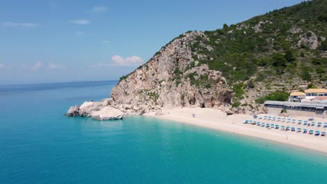 vista aérea de una hermosa playa de arena con sombrillas y suaves olas turquesas del océano en la temporada de verano en la playa de kathisma en la isla de lefkada