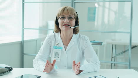 senior female doctor in headset giving online consultation