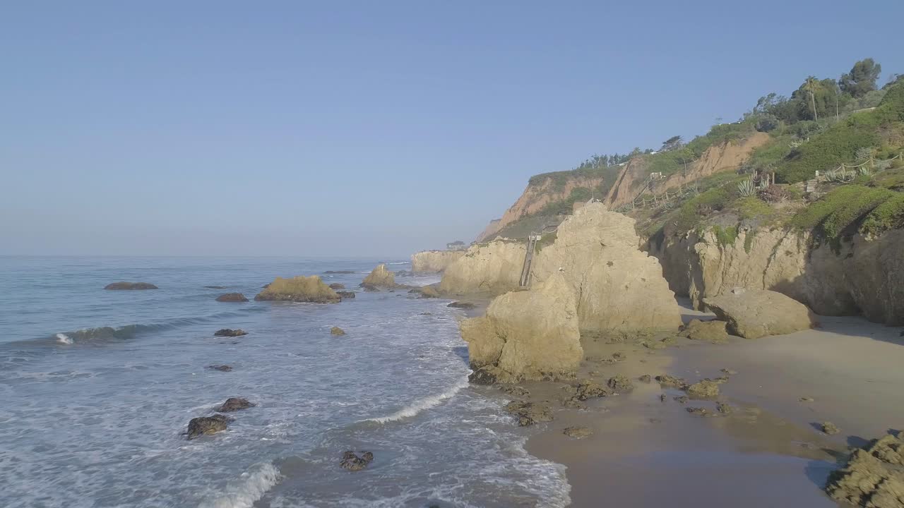 снимки с воздуха пляжа эль матадор над разбивающимися волнами и скалами туманным летним утром в малибу, калифорния