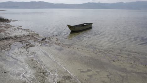 Video-with-a-drone-on-Lake-Skadar-in-Albania,-on-an-old-wooden-boat-in-the-foreground,-surpassing-it-in-different-planes-at-water-level