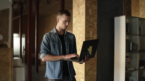 Attractive-Concentrated-Young-Business-Man-Is-Walking-With-Black-Laptop-In-His-Hand-And-Typing
