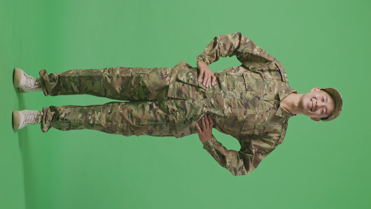 Full Body Of Asian Man Soldier Standing With Arms Akimbo Looking At Camera And Smiling In The Green Screen Background Studio