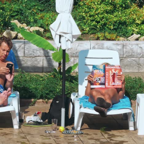 personas sentadas a la orilla de la piscina de un resort durante las vacaciones de verano
