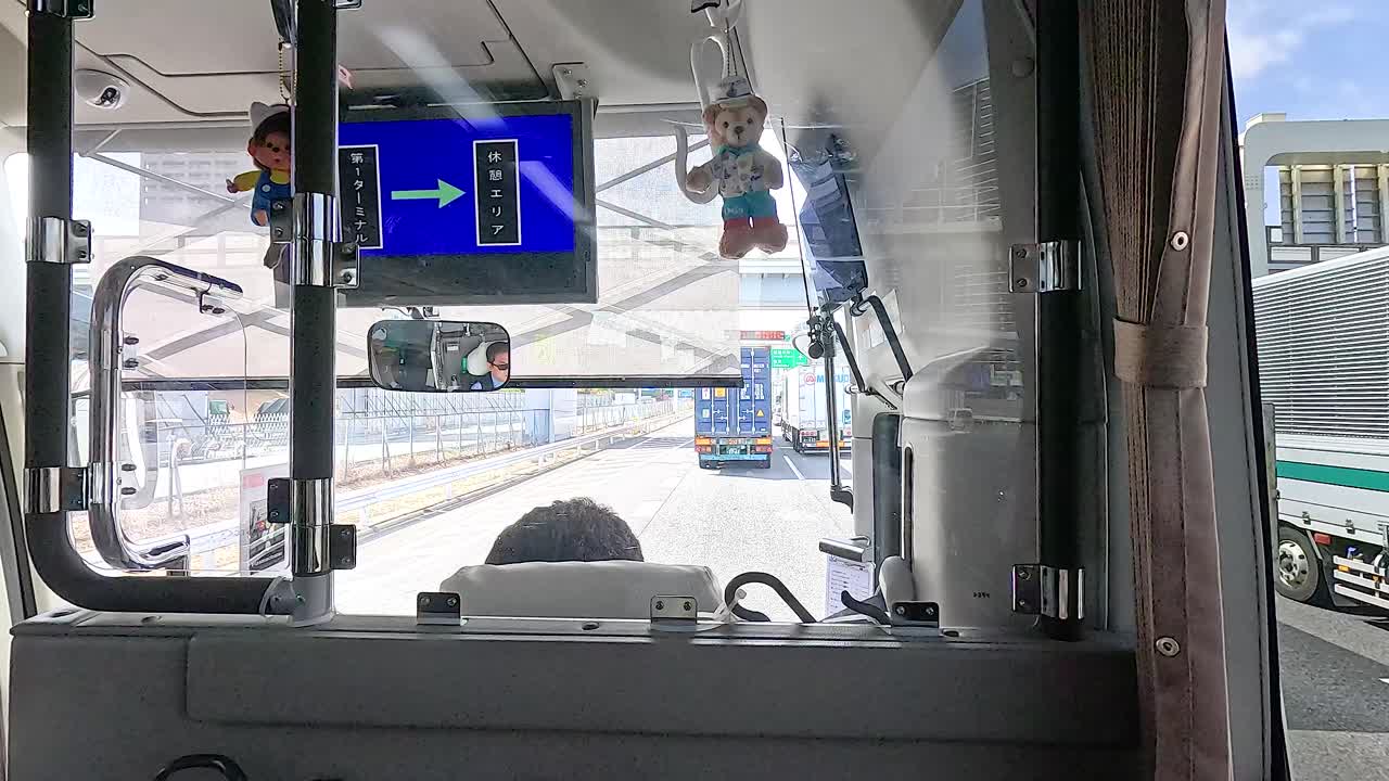 View from inside a bus navigating Tokyo's roads, with clear skies and bustling traffic