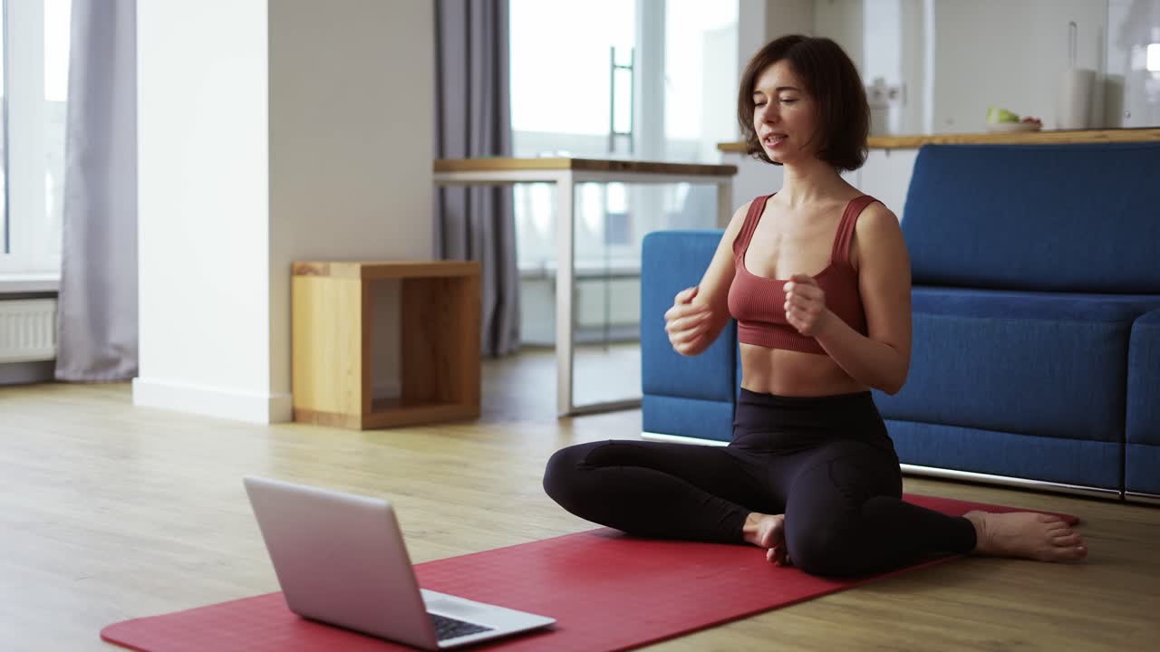 mujer practicando yoga con el entrenador por videoconferencia, calentando las articulaciones