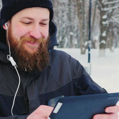 smiling man uses smartphone in winter park