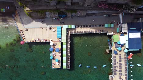 Imágenes-Aéreas-De-Drones-De-Arriba-Hacia-Abajo-Del-Club-De-Playa-En-El-Acantilado-Escarpado-De-La-Costa-De-Sorrento,-Campania,-Italia