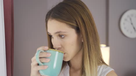 woman drinking coffee by the window.