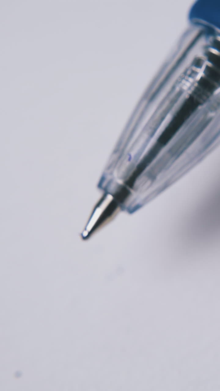 man fingers click button on blue automatic pen top in plastic case above white empty paper sheet macro