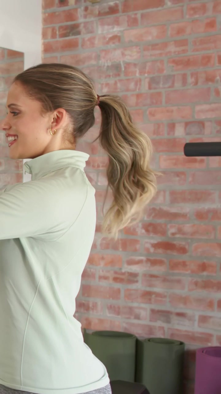 Vertical video: Entering green top woman cueing blue tee man doing squats at gym training with rack