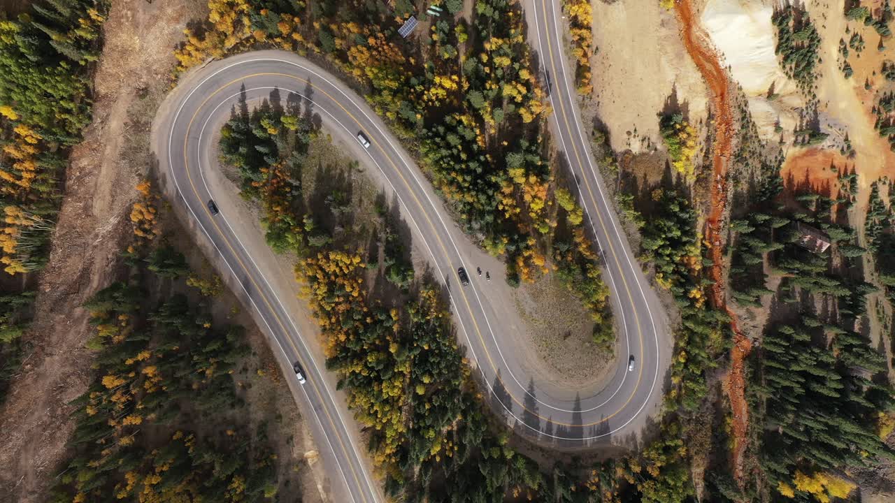 los viajeros navegan por un sinuoso y sinuoso camino de montaña durante los colores del otoño en colorado