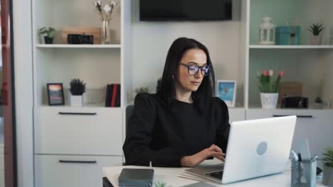 la joven y hermosa mujer de cabello oscuro está trabajando en una computadora portátil en una oficina