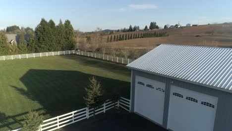 Metal-barn-with-green-pasture-and-white-fence-at-a-farm-in-Oregon