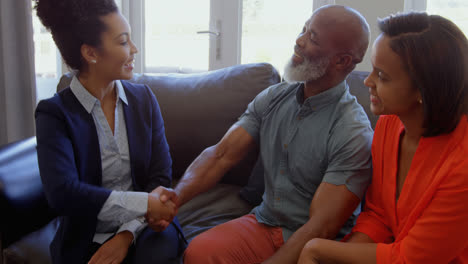 mixed race female real estate agent discussing over property with mature couple at home 4k