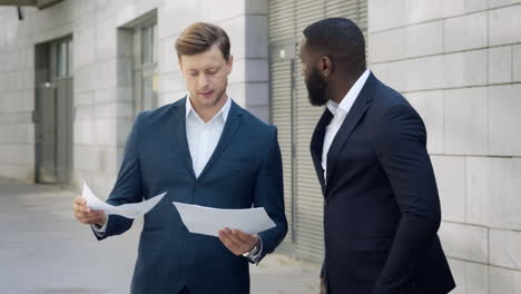 businessmen looking at documents on street. business men discussing graphics