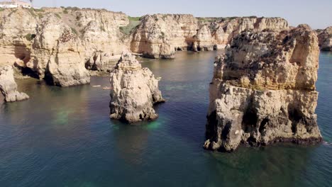 emerald ocean calm waters with eroded rock formations and cliffs in lagos, algarve, portugal