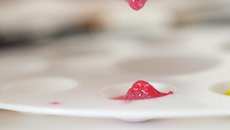 artist pouring red paint onto a palette