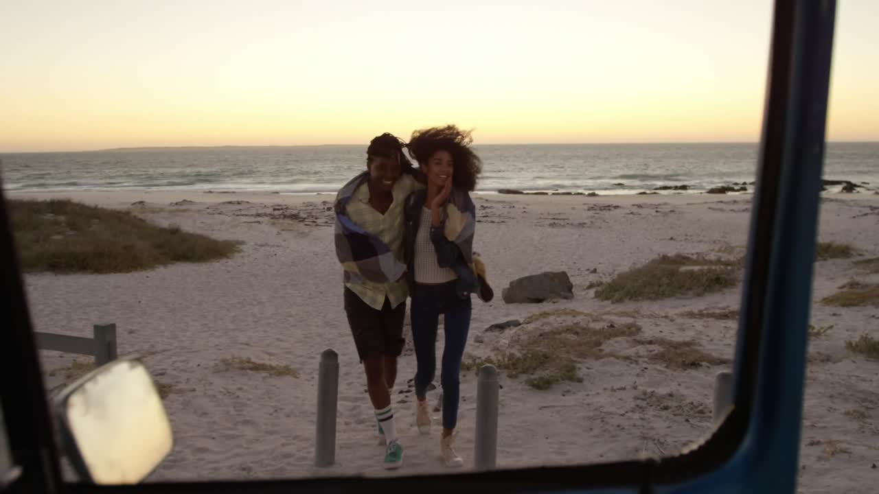 pareja envuelta en una manta y caminando juntos cerca de una camioneta 4k