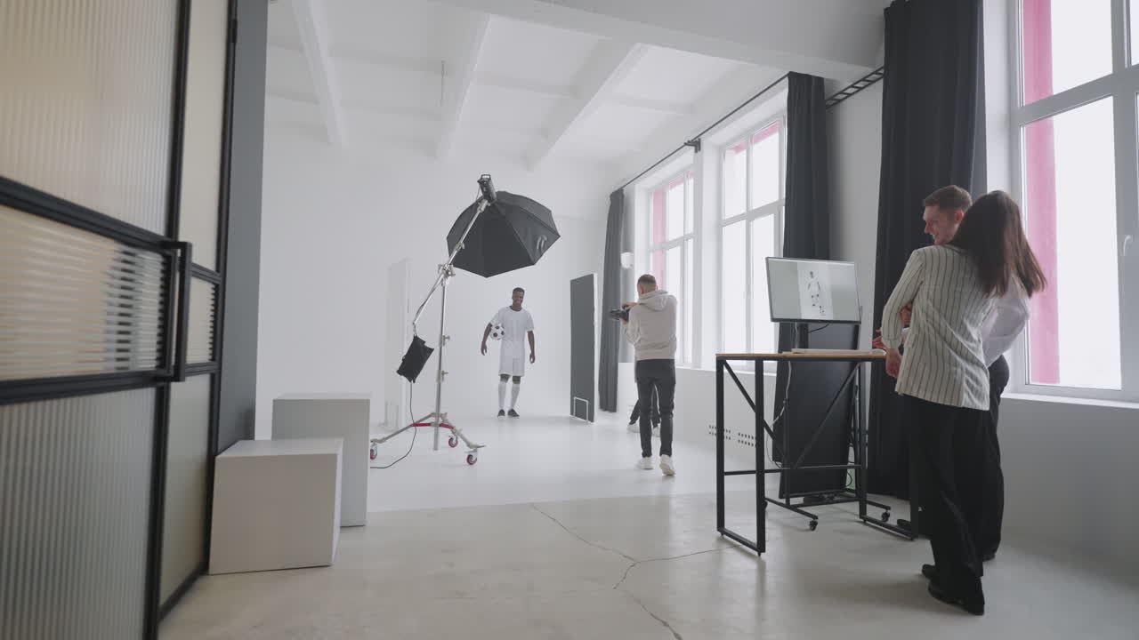 편집자들은 스포츠 사진 세션에 대한 사진을 논의하고 있습니다. 잡지 흑인 축구 선수가 포즈를 취하고 있습니다.