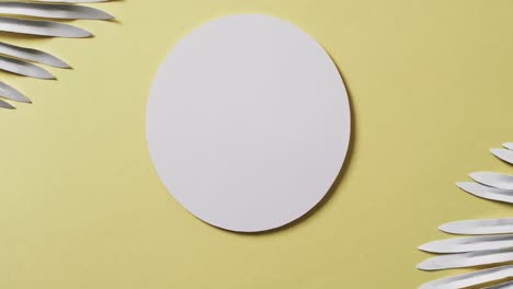 Video-of-white-plant-leaves-and-white-circle-with-copy-space-on-yellow-background