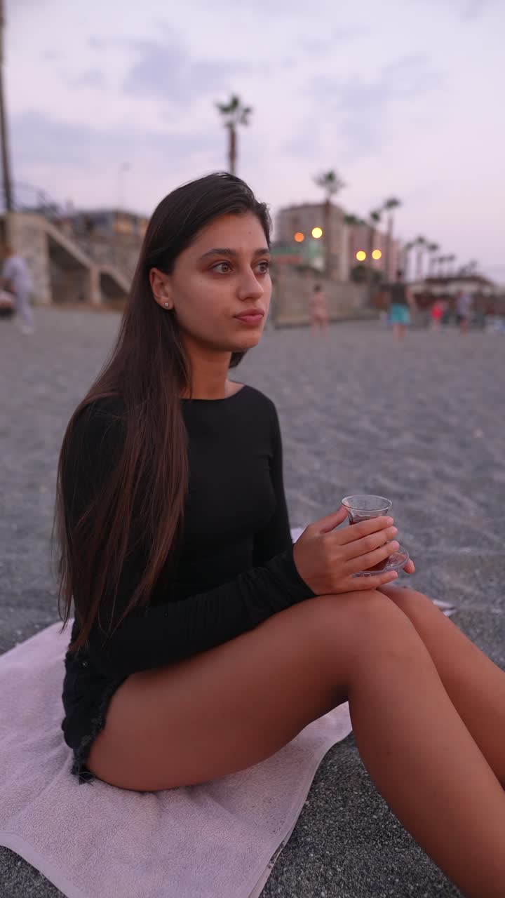 mujer disfrutando del té en la playa al atardecer