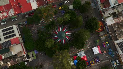 aerial top down shot of independence day in ajijic, jalisco, mexico. decorated park with colors of méxico. solar panels on roof of houses in town.