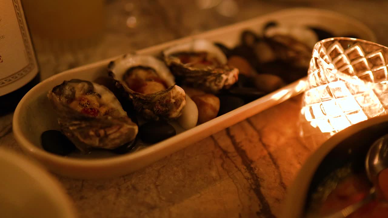 Oysters served on a platter beside a glowing candle, creating a warm, intimate dining atmosphere with soft lighting