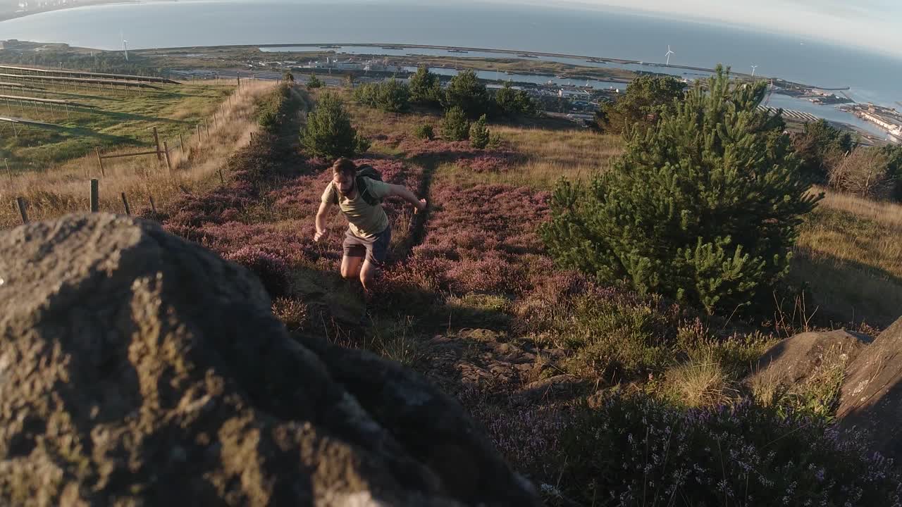 corredor de cross country corriendo cuesta arriba con océano y paneles solares