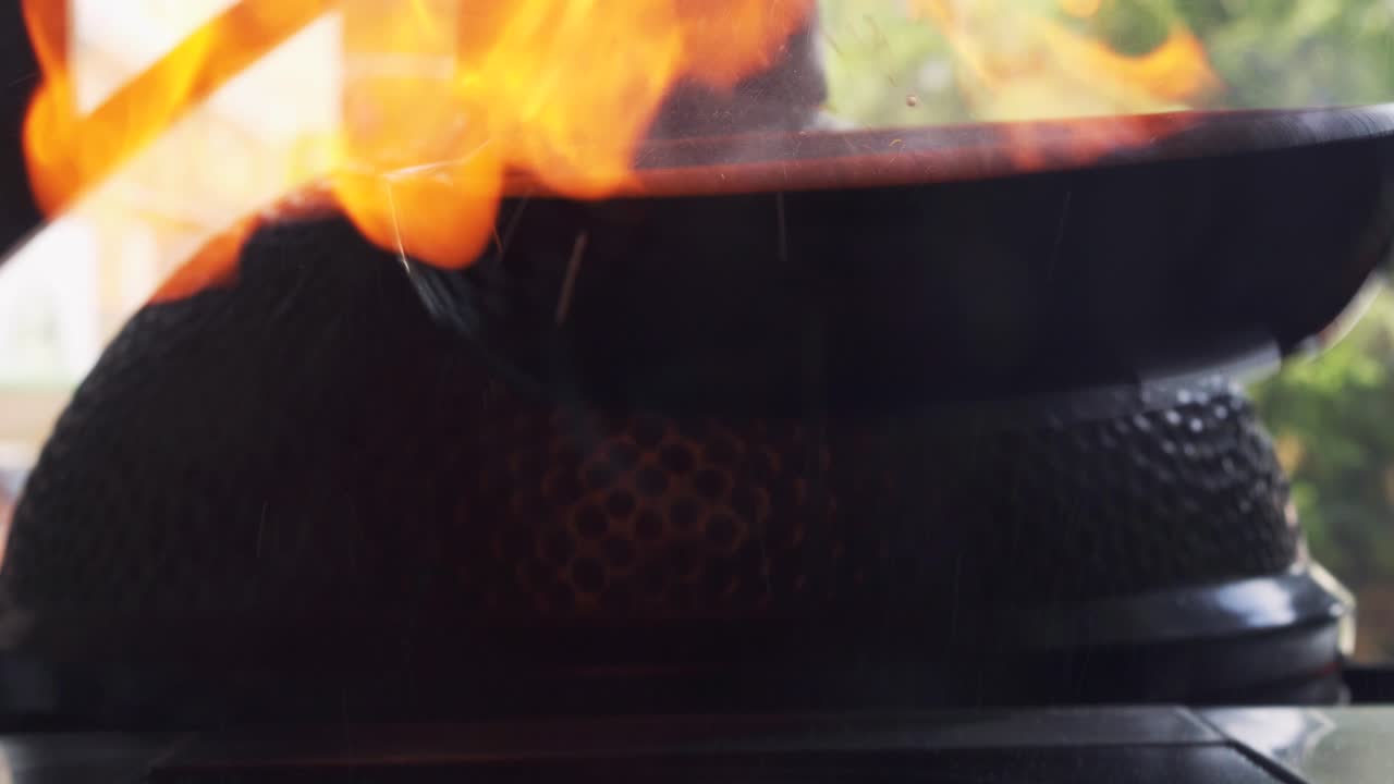 Professional shef in black gloves cooking with flame in a frying pan some food with alcohol on a stove outside