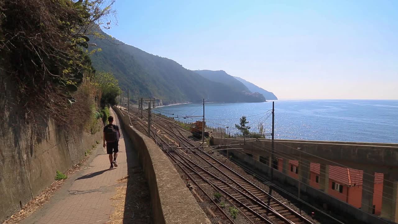 el hombre camina por el paseo junto al ferrocarril costero en cinque terre, italia