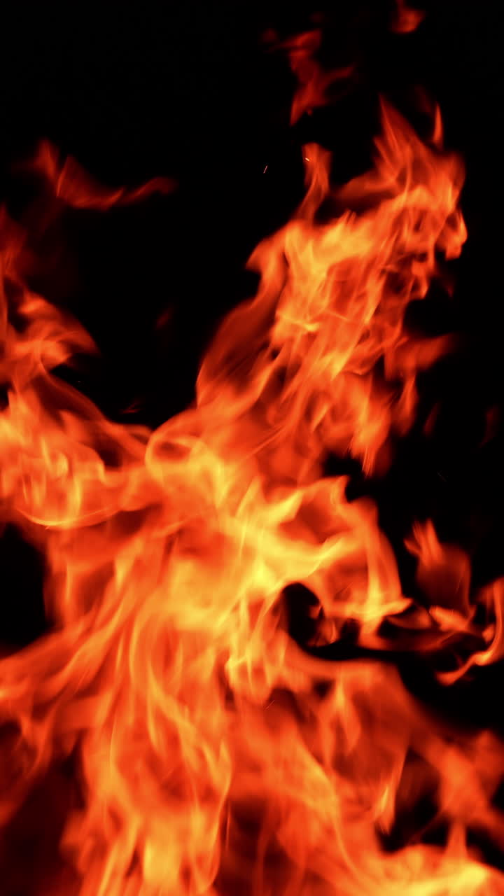 Beautiful orange fire burning at night. Hot fire flames going up on the wind. Vertical video