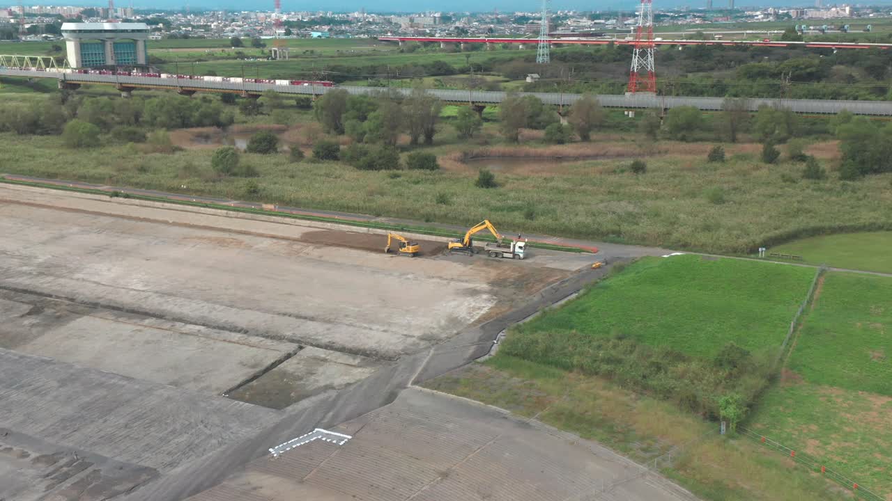 dos excavadoras industriales excavando en el suelo con un tren que pasa al fondo en saitama, japón