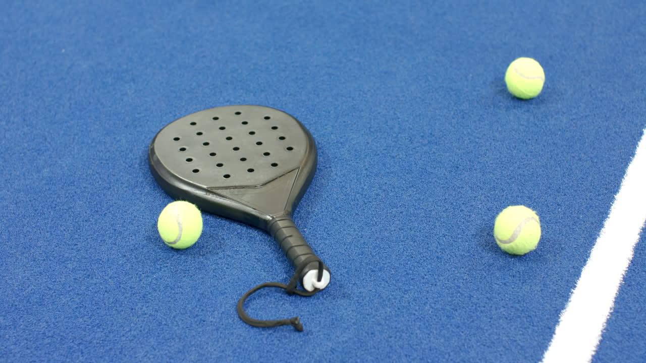 Padel racket and tennis balls on blue indoor court, ready for match, copy space