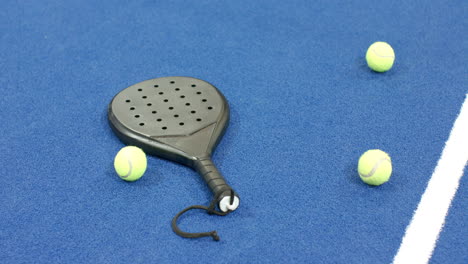 padel racket and tennis balls on blue indoor court, ready for match, copy space