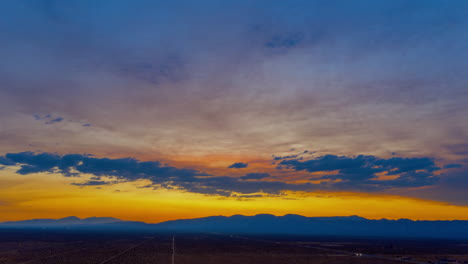 descending aerial hyperlapse of a dramatic golden sunset over the mojave desert landscape in summer