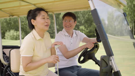 Asian-couple-talking-and-laughing-on-a-golf-cart