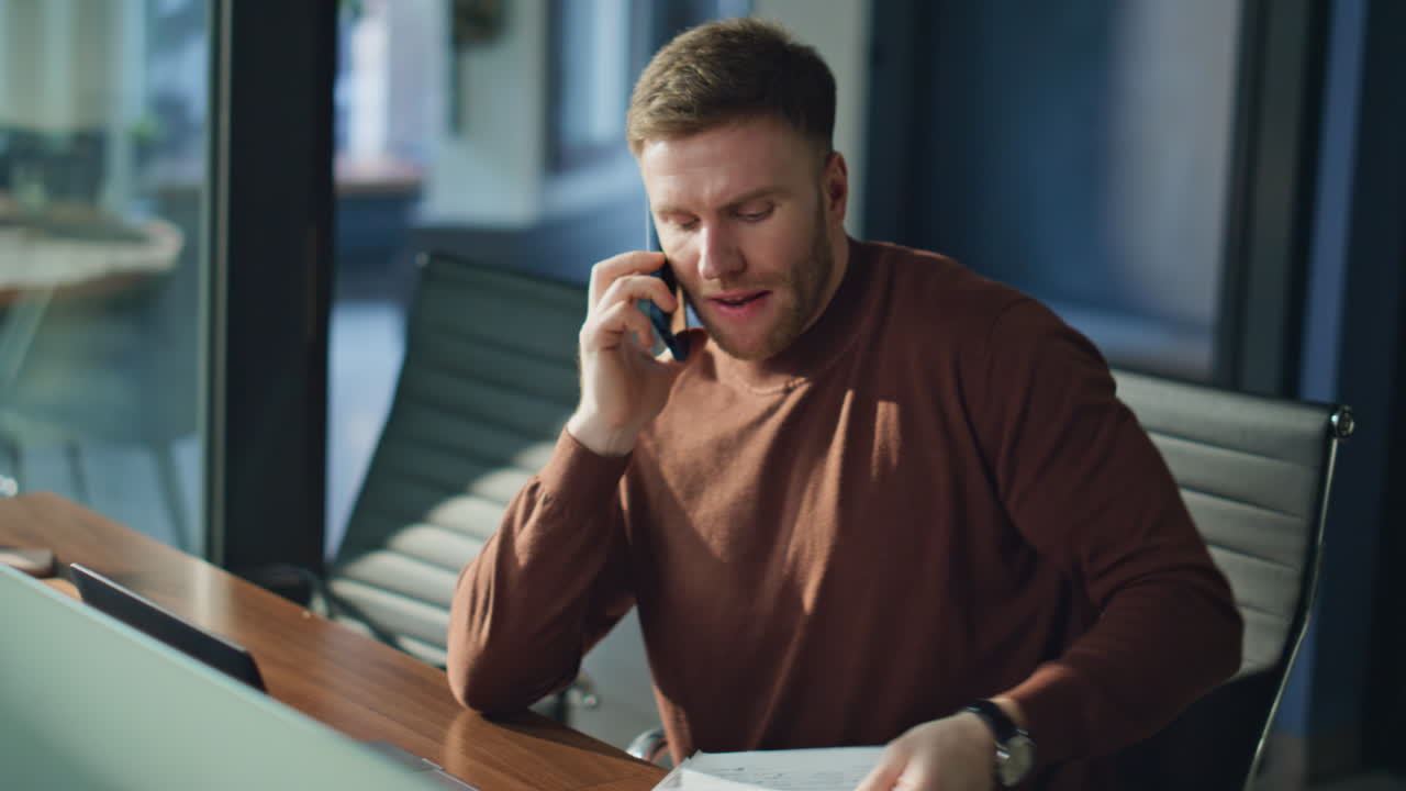 Displeased entrepreneur speaking smartphone holding documents at office closeup