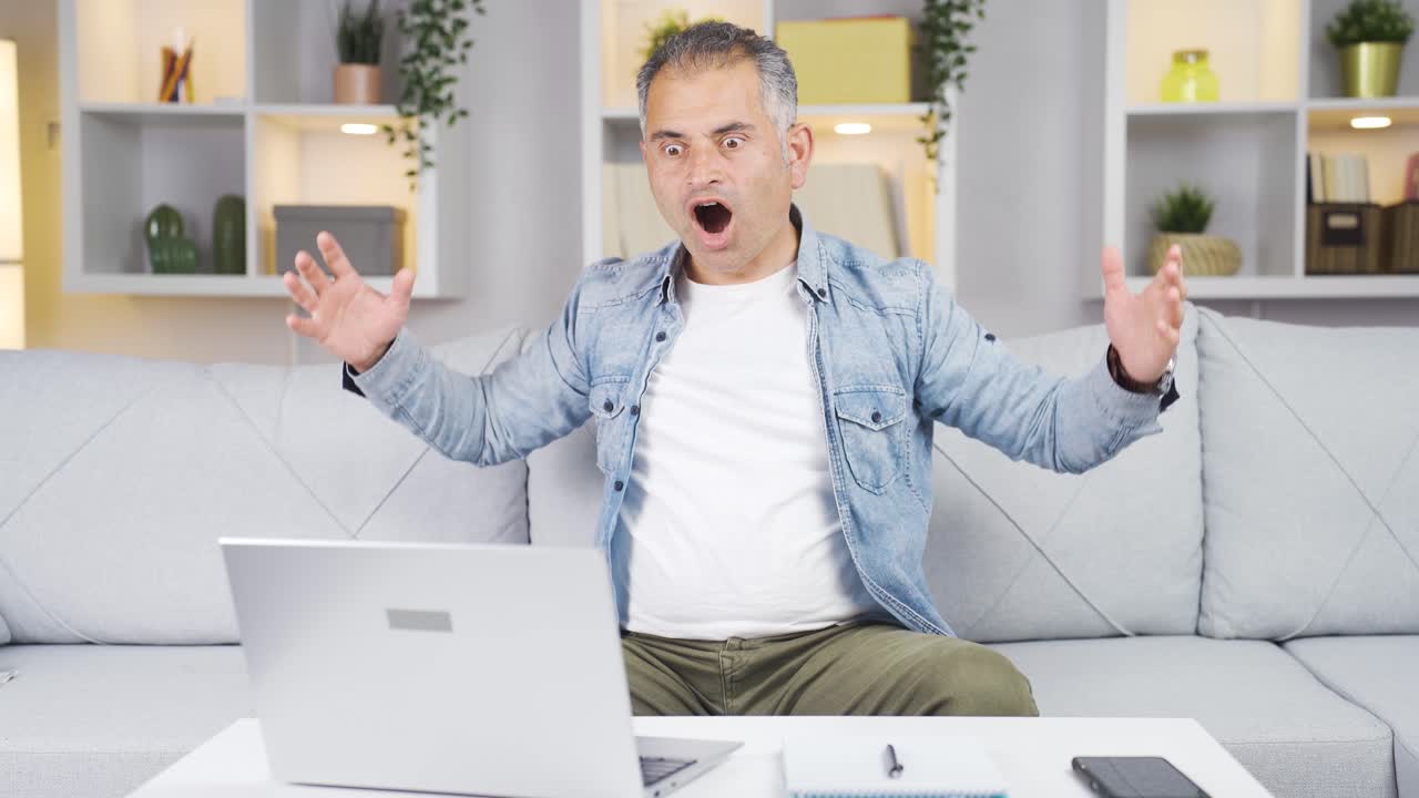 hombre mirando la computadora portátil con asombro.