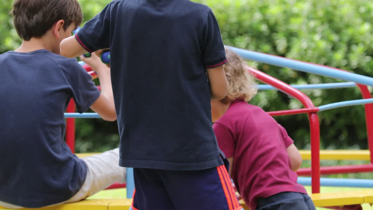 niños en el patio de recreo con carrusel girando