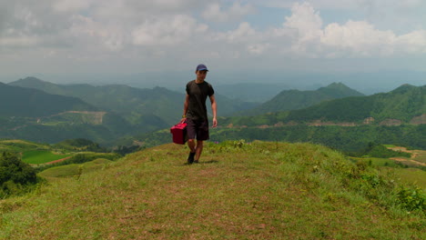 Abstract-concept-video-of-male-in-nature-of-lush-green-hilltop-carrying-old-TV