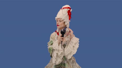 portrait of courtier lady in white vintage lace dress and wig is dries hair with a hair dryer. young woman posing in studio with blue screen background. close up. slow motion ready 59.94fps