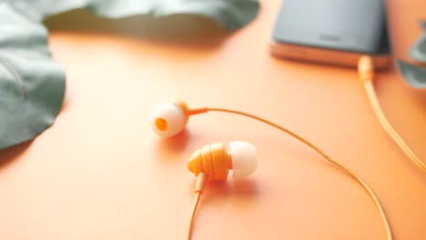 orange headphones and smartphone on orange background