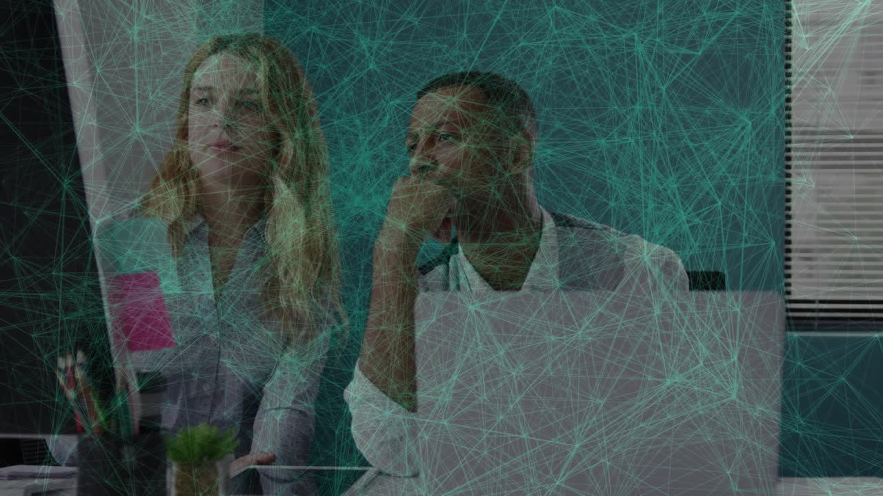 Woman pointing at monitor and man listening in office, network graphic highlighting business data