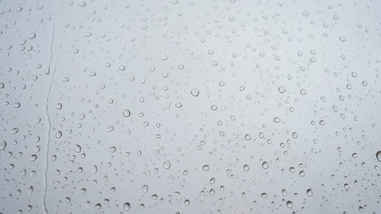 un metraje en cámara lenta de fuertes gotas de lluvia aterrizando en un vidrio de la ventana